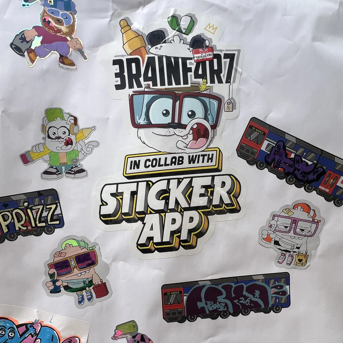 Vegg dekket av håndfargelagte die-cut klistremerker fra Brainfart x StickerApp og etiketter med S8 World-toget med graffititagger