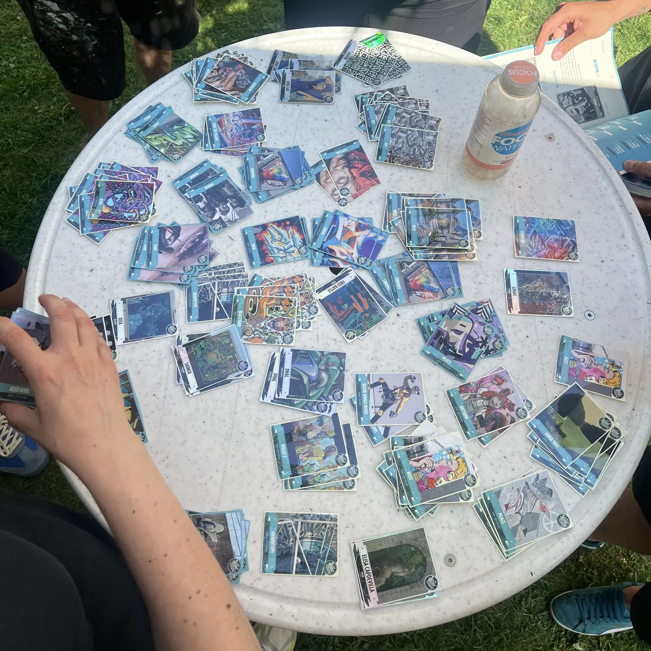 Festivalbesøkende fyller blå klistremerkealbum med samlekort av klistremerker med gatekunst, spredt utover et rundt bord