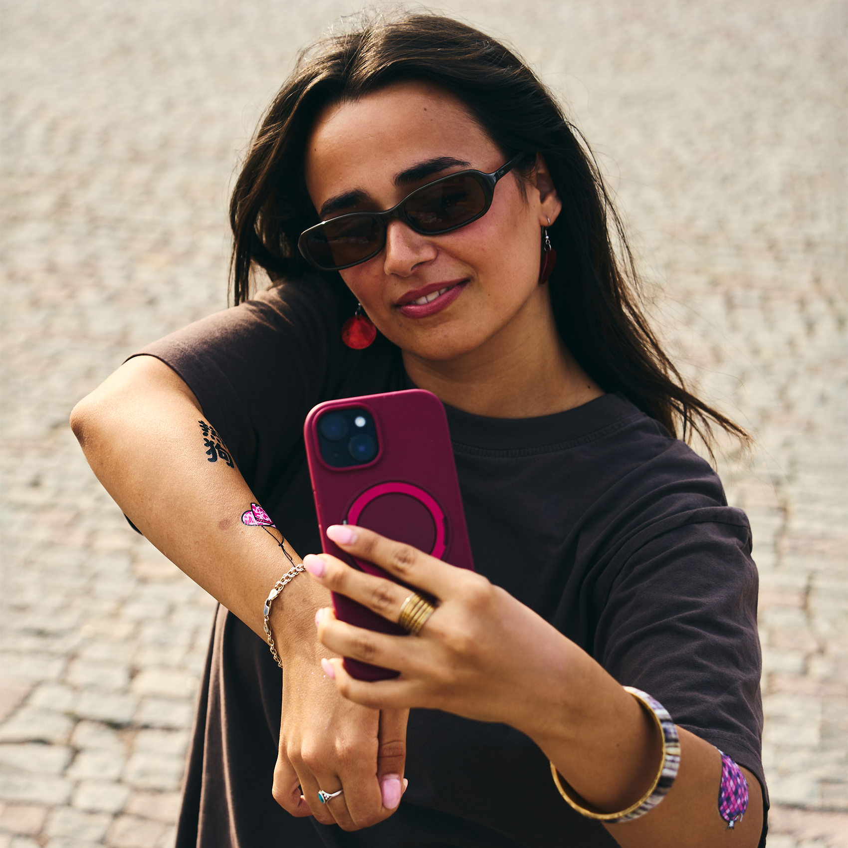 Woman taking a selfie while wearing temporary tattoos on her arm