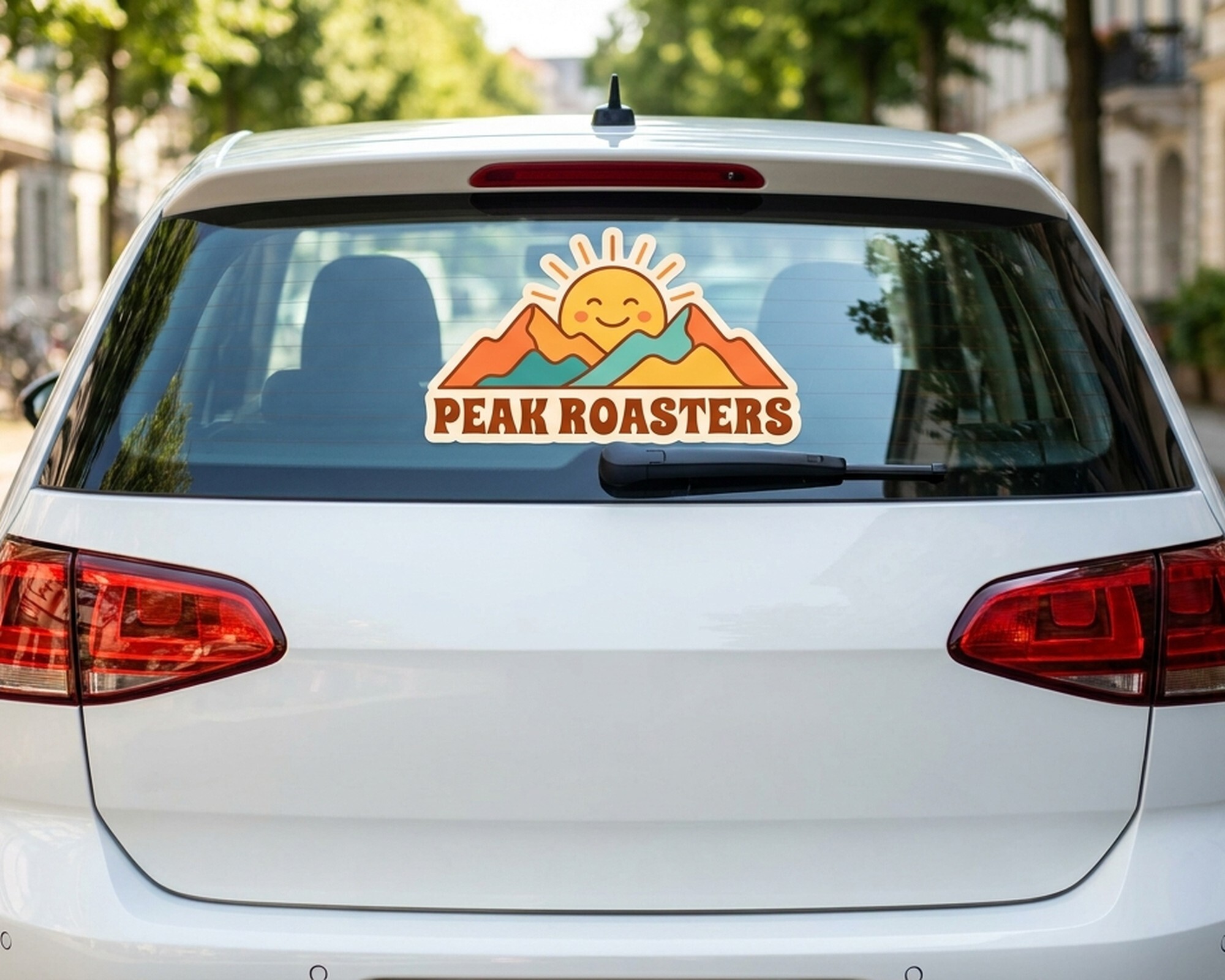 Egen dekal i die-cut med en logo med sol og fjell og teksten "Peak Roasters" på bakruten til en bil