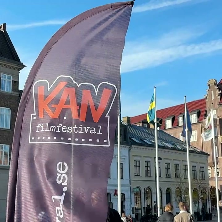 Beachflagg for KAN filmfestival foran historiske bygninger og flagg på et torg i Lund